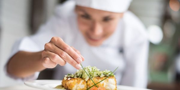 Cook decorating a plate and putting the ultimate touches - focus on foreground