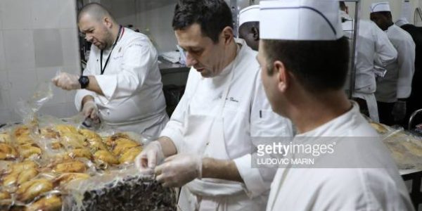 Chef of the Elysee presidential Palace Guillaume Gomez (L) prepares chicken with Nigerien commis chefs, for a Christmas dinner with the French president and French troops participating in the France's Barkhane mission in Africa's Sahel, on the French Air Force base in Niamey, on December 22, 2017. / AFP PHOTO / LUDOVIC MARIN        (Photo credit should read LUDOVIC MARIN/AFP via Getty Images)