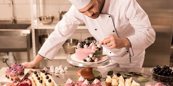 portrait of confectioner decorating cake in restaurant kitchen